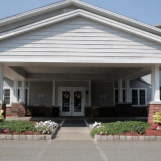 A building entrance with a pathway leading up to it, surrounded by flowers.