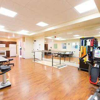 A spacious rehabilitation room equipped with various exercise machines and tools.