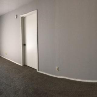 A minimalist empty room with carpet flooring and a closed door.