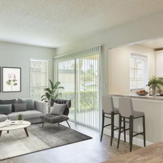 A modern living room with a cozy sofa, coffee table, and bar stools, featuring an open design with natural light.