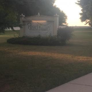 An inviting sign at dusk, surrounded by lush grass and trees.
