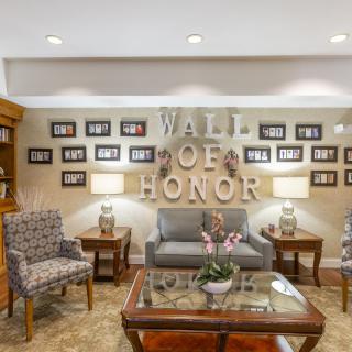 A cozy lounge area featuring a 'Wall of Honor' adorned with framed photos and elegant furnishings.
