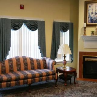 A traditional living room with a striped sofa, elegant curtains, and a cozy fireplace.
