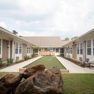 A serene courtyard with a central pathway flanked by buildings and greenery.