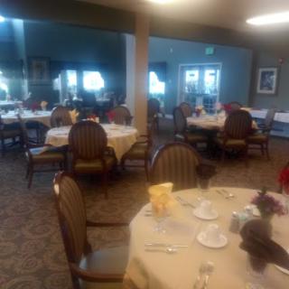 A cozy dining area set up for a meal, featuring tables with tablecloths and chairs.