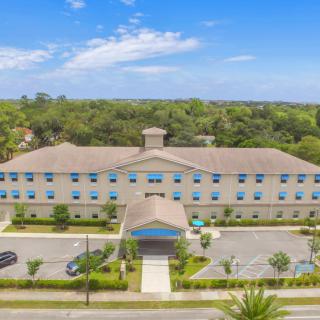 Aerial view of a large building with a parking lot surrounded by trees.