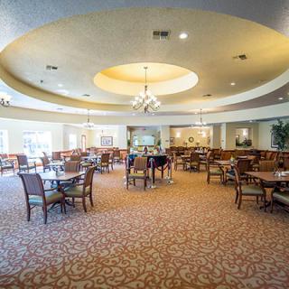 A spacious dining area with tables and chairs, featuring elegant ceiling lighting.