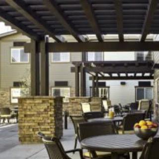 A stylish outdoor patio area with tables and chairs under a pergola.