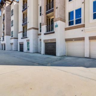 A modern apartment complex with multiple garage doors and large windows.