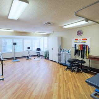 A spacious fitness studio equipped with various exercise equipment, perfect for physical therapy and rehabilitation.
