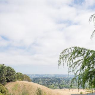 A scenic view of rolling hills and a distant landscape under a partly cloudy sky.
