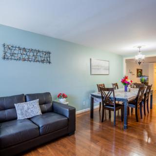 A cozy living and dining area featuring a dark sofa, elegant dining set, and decorative wall art.