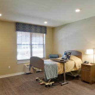 A clean and well-lit hospital room with a single bed and medical equipment.