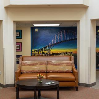 A cozy lobby area featuring a leather couch, a small round table, and a colorful mural on the wall.