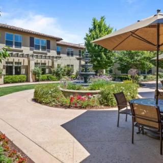 A tranquil courtyard with a central fountain, surrounded by landscaped gardens and outdoor seating.