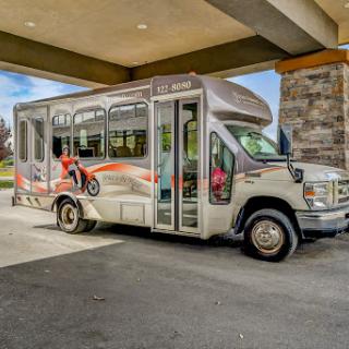 A colorful shuttle bus parked under a canopy, ready for passengers.