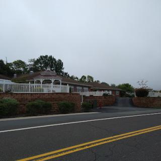 A peaceful residential house shrouded in fog, seen from the road.
