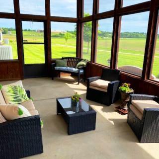 A cozy sunroom with comfortable seating and expansive views of the outdoors.