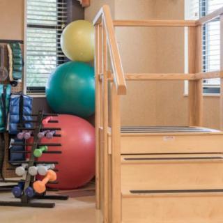 A gym space featuring exercise balls, dumbbells, and a small staircase for fitness or rehabilitation exercises.