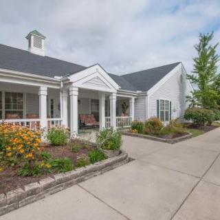 A scenic view of a residential house with a porch and landscaped front yard.