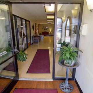 A welcoming entrance with glass doors, potted plants, and a red carpet leading into the building.