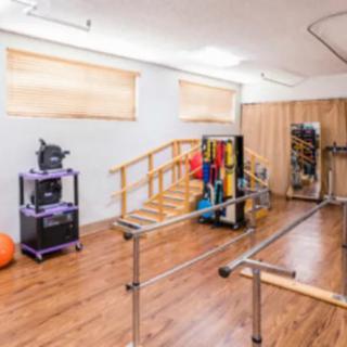 A rehabilitation room equipped with parallel bars and various physical therapy tools.