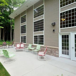 A modern patio with colorful chairs against a building's glass windows, surrounded by trees.