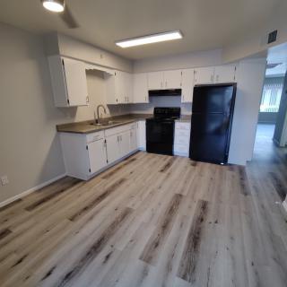 A modern kitchen with white cabinets and wood flooring.