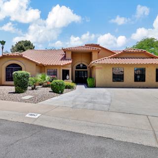A beautiful residential home with a landscaped front yard under a bright blue sky.