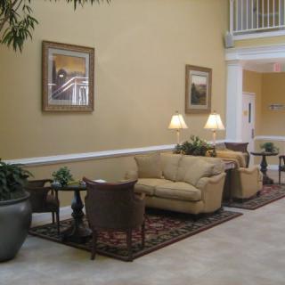 An elegant lobby with a cozy seating area featuring sofas, a carpet, indoor plants, and artwork on the walls.