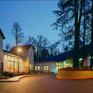 A well-lit building surrounded by tall trees during the evening.