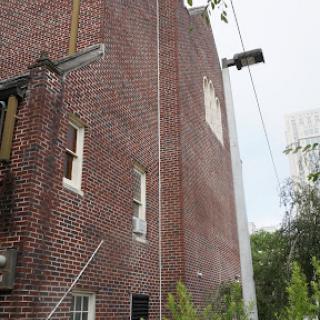A view of a brick building featuring windows and a ladder against its facade.