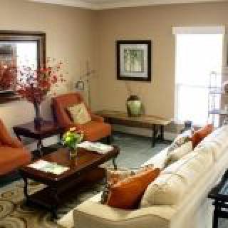 A cozy living room featuring a sofa and armchairs arranged around a coffee table, with warm decor accents and natural lighting.