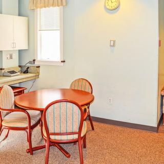 A cozy dining area with a round wooden table and chairs near a kitchenette.