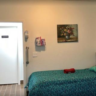 A cozy bedroom with a bed, wall painting, and a door.