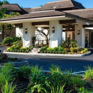 A well-landscaped entrance of a modern building, possibly a hotel.