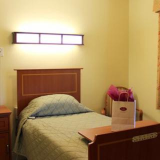 A minimalist bedroom with a single bed and wall-mounted lamp.