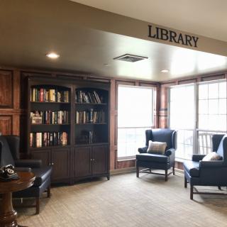 A cozy library corner with comfortable seating and a bookshelf filled with books.