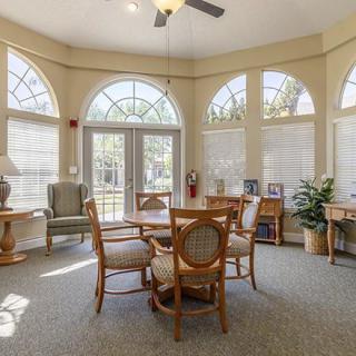 A bright living room with large windows, a round table, and comfortable seating.