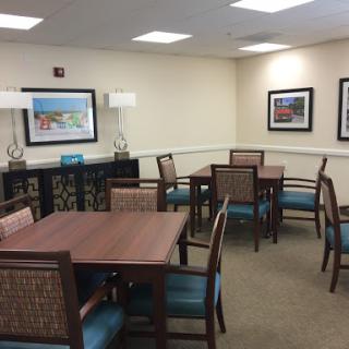 A spacious and well-lit dining area featuring wooden tables, comfortable chairs, and decorative artwork on the walls.