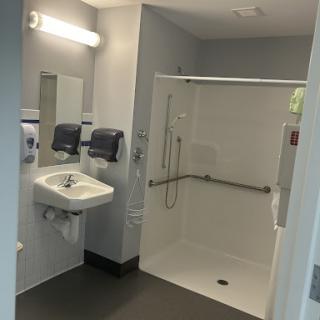A clean and modern bathroom featuring a shower and sink, designed for accessibility.