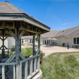 A scenic outdoor area with a wooden gazebo and a modern building in the background.