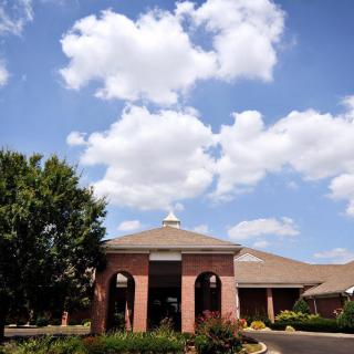 A charming brick building under a bright blue sky with fluffy clouds.