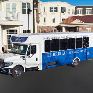 A blue and white shuttle bus parked on a street in front of buildings.
