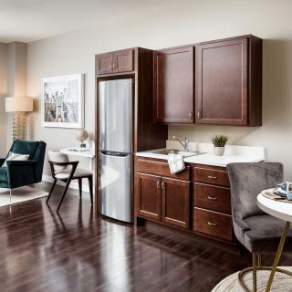 A modern living room and kitchen area with dark wood cabinets and hardwood flooring.