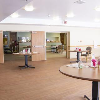 An empty dining area with tables and chairs arranged on a wooden floor.