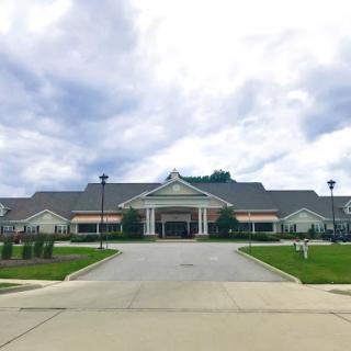 A modern healthcare facility surrounded by well-maintained landscaping under a cloudy sky.