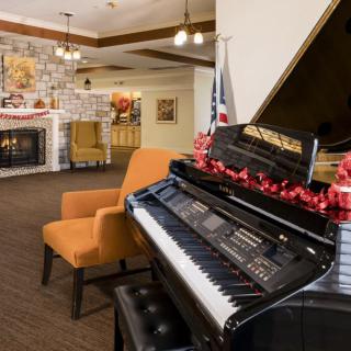 A cozy lounge with a grand piano, comfortable seating, and a warm fireplace.