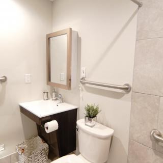 A minimalist bathroom with a sink, mirror, and toilet featuring simple decor.