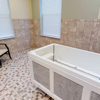 A spacious bathroom with a modern bathtub and tiled flooring.